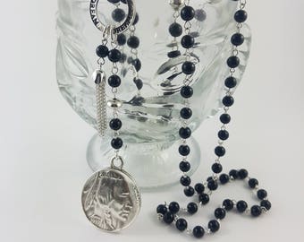 Long, black riverstone beaded necklace with sterling silver beads, coin charm, tassel and affirmation ring.