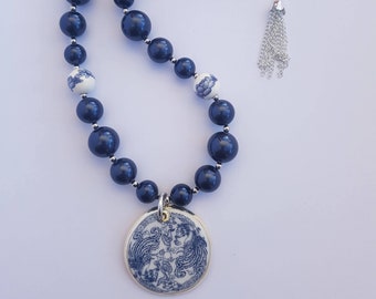 Classic-style necklace of night blue Swarovski pearls with blue and white porcelain beads and porcelain pendant featuring two phoenix.