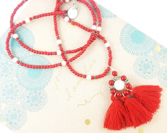 Long necklace of red turquoise gemstone beads with Swarovski pearls and a large pendant of cotton tassels with a Swarovski pearl centre.