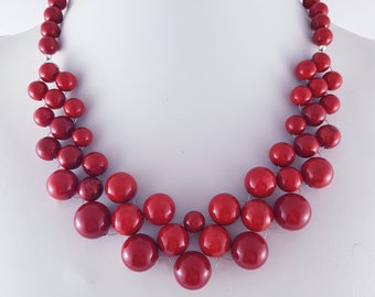 Hand-woven necklace of red riverstone beads with red shell pearls.