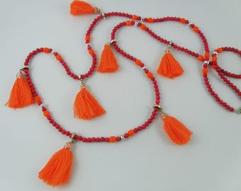Long boho-inspired necklace of pink riverstone gemstone with orange Swarovski pearls and orange cotton tassels.