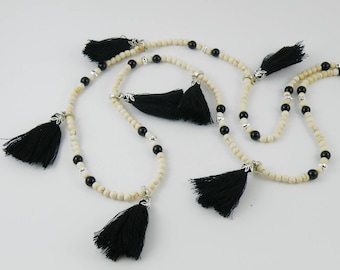Long boho-inspired necklace of white howlite gemstone with black riverstone and black cotton tassels.
