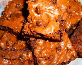 May include: A plate of freshly baked chocolate brownies with chocolate chips. The brownies are a rich, dark brown color and have a slightly glossy finish. The chocolate chips are scattered throughout the brownies and add a touch of sweetness.