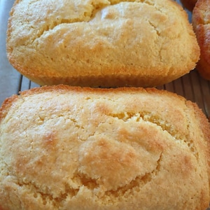 May include: Three golden brown cornbread loaves on a wire rack. The loaves are slightly rounded and have a slightly rough texture.