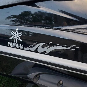 May include: A black Yamaha jet ski with a silver Yamaha logo and a silver flame design.