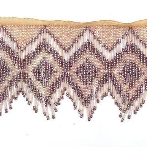 May include: A beaded fringe trim with a geometric pattern in shades of pink and purple. The fringe is made of small, round beads that are strung together on a thin thread. The trim is approximately 1 inch wide and has a scalloped edge.