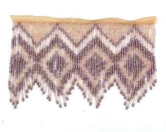 May include: A beaded fringe trim with a geometric pattern in shades of pink and purple. The fringe is made of small, round beads that are strung together on a thin thread. The trim is approximately 1 inch wide and has a scalloped edge.