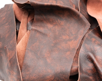 May include: A collection of dark brown leather scraps featuring a mottled, marbled texture with lighter reddish-brown highlights. The pieces show a smooth, finished grain on the top side and a soft, fibrous suede texture on the underside.