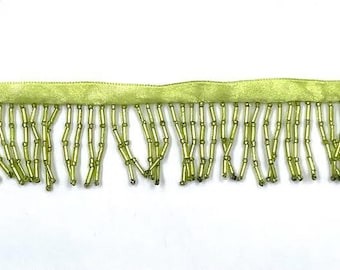 May include: A lime green beaded fringe trim with a satin backing. The fringe is made of small, round beads strung together in a vertical pattern.