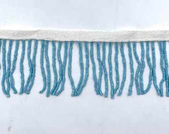 May include: A length of light blue beaded fringe trim with a white fabric backing.