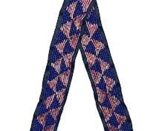 May include: A blue and pink patterned fabric ribbon with a geometric design. The ribbon is folded in half and tied in a knot.