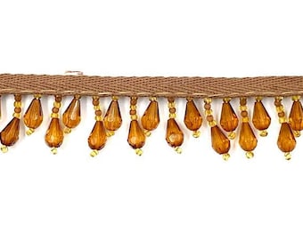 May include: Brown decorative trim with a woven base and dangling amber-colored teardrop beads. The trim is suitable for embellishing clothing, home decor, or craft projects. The beads are suspended from small gold-colored beads.
