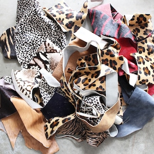 May include: A pile of colorful animal print fabric scraps, including leopard, zebra, and snake patterns. The scraps are arranged in a random, chaotic fashion, creating a visually interesting and textured composition.