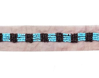 May include: A close-up of a beaded trim with alternating rows of brown and turquoise beads.