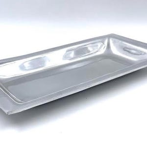 May include: A silver rectangular serving tray with a slightly raised center and a smooth, reflective surface.