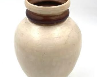 May include: A cream-colored ceramic vase with a brown rim and a brown band around the middle.