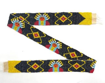 May include: A beaded trim with a black background, yellow accents, and colorful geometric patterns. The trim features repeating designs of stylized figures with red, yellow, blue, and white beads.