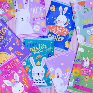 Puede incluir: Una colección de diez bolsas de regalo de temática pascual de colores con conejos, huevos y flores. Las bolsas tienen diferentes diseños y dicen "Feliz Pascua" y "Pascua alegre".