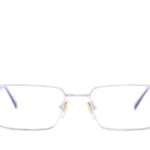 May include: A pair of rectangular spectacles with a thin, silver-coloured metal frame. The glasses feature clear lenses, a slim bridge, and adjustable nose pads. The temples are slender and connect to the front frame with a simple hinge mechanism.