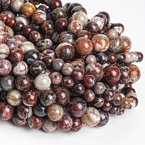 May include: A strand of red, brown, and white agate beads. The beads are round and have a natural, polished finish.