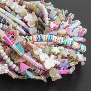 May include: A collection of colorful shell beads in various shapes, including stars, hearts, and triangles. The beads are strung on a white cord and are perfect for making jewelry.
