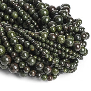 May include: A close-up of a pile of dark green gemstone beads. The beads are round and have a smooth, polished finish.