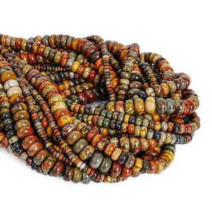 May include: A collection of multi-colored stone beads in shades of brown, red, green, and yellow. The beads vary in size and shape, creating a textured and layered appearance. The beads are strung together, forming a necklace or bracelet.