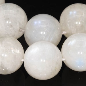 May include: A strand of white moonstone beads, each bead is round and smooth. The beads are strung on a white thread.