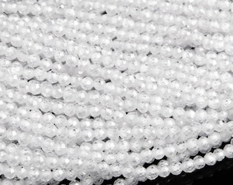 May include: A strand of white faceted quartz beads. The beads are small and round, and they have a smooth, polished finish.