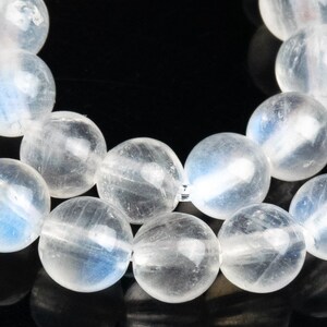 May include: A strand of white moonstone beads. The beads are round and smooth, with a slight iridescent sheen.