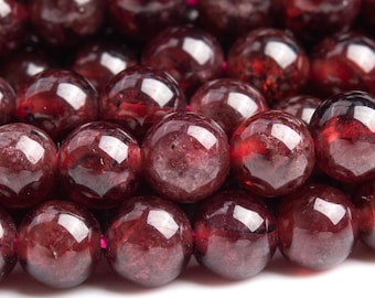 May include: A strand of deep red gemstone beads. The beads are round and smooth, with a slightly translucent quality.