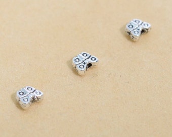 May include: Three silver butterfly-shaped beads with a textured surface.