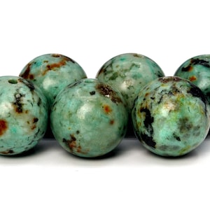 May include: Six round, green and brown speckled beads. The beads are smooth and have a natural, organic look.