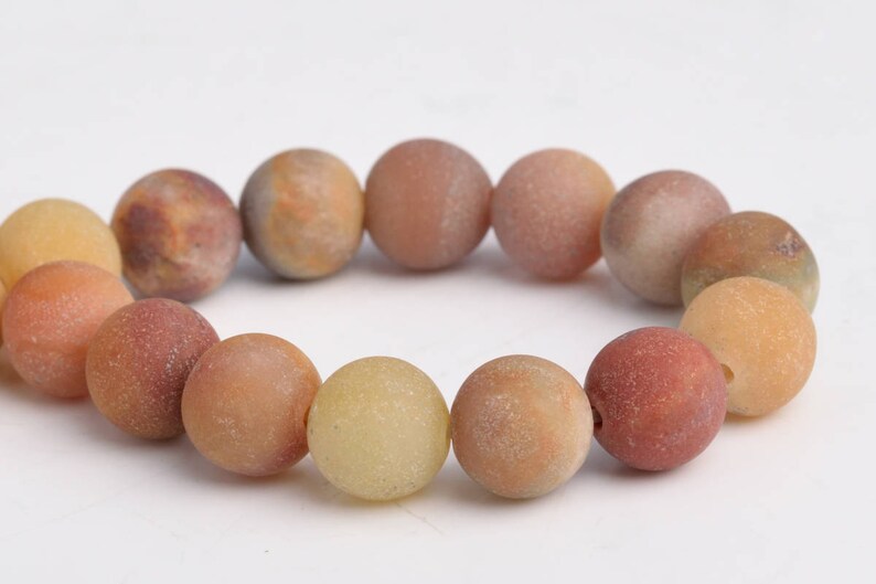 K&ouml;nnte beinhalten: Ein Armband aus runden, glatten Agatsteinen in Braun-, Gelb- und Oranget&ouml;nen.
