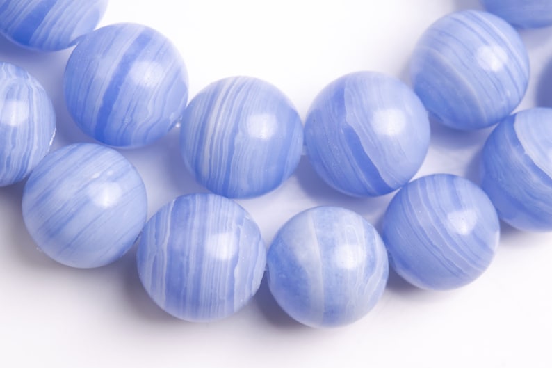 K&ouml;nnte beinhalten: Eine Reihe von blauen Achatperlen mit wei&szlig;en Streifen. Die Perlen sind rund und glatt.