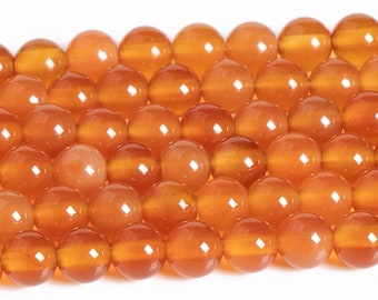 May include: A strand of smooth, round, orange carnelian beads. The beads are all approximately the same size and have a glossy finish.