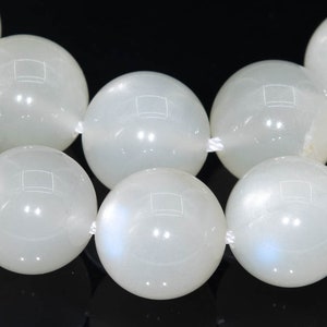May include: A strand of white moonstone beads. The beads are round and smooth, with a subtle iridescent sheen.