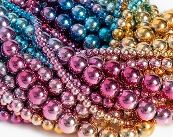 May include: Close-up of a collection of iridescent beads in a rainbow of colors. The beads range in size and are arranged in curved rows, showcasing a gradient from blue to pink to gold.