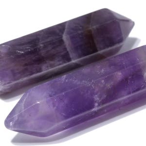 May include: Two purple amethyst crystal points, each with a smooth, polished surface and a pointed tip. The crystals are approximately 2 inches long.