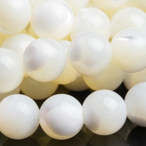 May include: A strand of white mother of pearl beads. The beads are round and smooth, with a slight iridescent sheen.