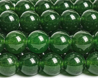May include: Close-up of a collection of polished, round, dark green beads. The beads have a glossy finish and reflect light, creating highlights. The beads are arranged closely together, suggesting a strand or collection of jewelry components.