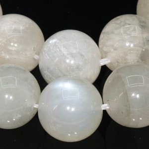 May include: A strand of white moonstone beads. The beads are round and smooth, with a slight iridescent sheen.