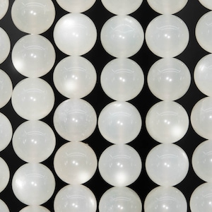 May include: A strand of white moonstone beads, each bead is round and smooth, with a subtle shimmer.