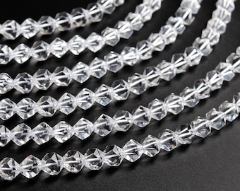 May include: A strand of clear faceted crystal beads. The beads are arranged in a row and are all the same size and shape. The beads are strung on a clear thread.