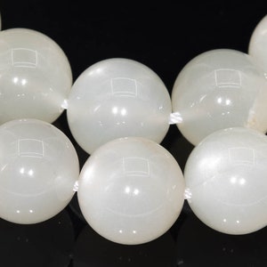 May include: A strand of white moonstone beads. The beads are round and smooth, with a pearly sheen.