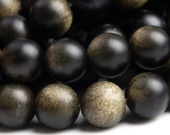 Puede incluir: Primer plano de una hebra de cuentas de madera negra con un sutil brillo dorado. Las cuentas son redondas y lisas, y están dispuestas en un patrón de primer plano.