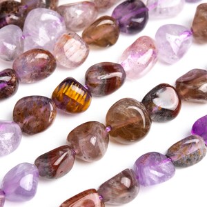 May include: A strand of purple, brown and gold gemstone beads. The beads are smooth and have a natural, tumbled finish. They are strung on a clear elastic cord.