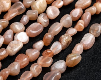 May include: A strand of smooth, peach-colored sunstone beads. The beads are tumbled and have a natural, irregular shape.