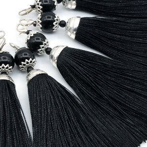 以下が含まれることがあります： 銀色の金属ビーズとキャップが付いた、黒いタッセルトリムのセット6個。タッセルは柔らかく絹のような素材で作られており、どんなプロジェクトにもエレガントなタッチを加えるのに最適です。