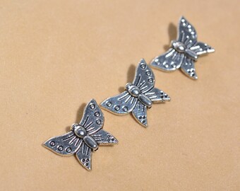 May include: Three silver butterfly charms with detailed wings and a textured surface.